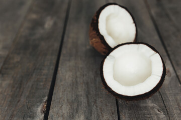 Broken coconuts on gray wooden background. White coconut pulp