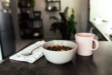Pink coffee cup, chopped fruits in bowl blueberries, spoon on towel in kitchen