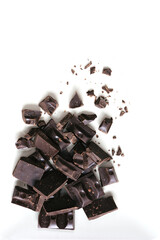 Pieces of dark chocolate bar on a light background. Top view, flat lay, copy space.