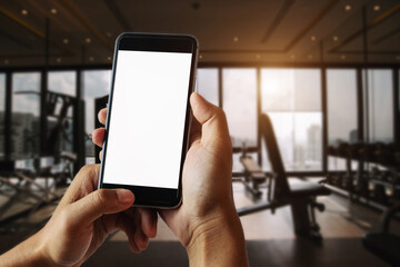 A man hand holding smart phone device in the fitness room
