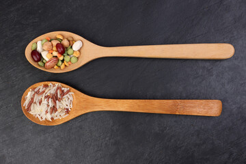 Mixed beans multi grain low glycaemic index healthy rice grain basmati millet buckwheat red rice in wooden spoon on black background