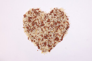 Mixed low glycaemic index healthy rice grain basmati millet buckwheat red rice hart shape on white background