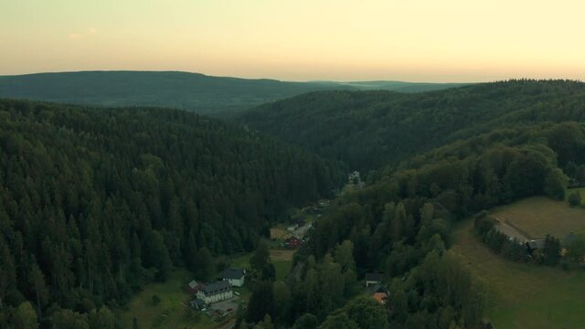 Rural houses in valley between high hills covered by evergreen forests