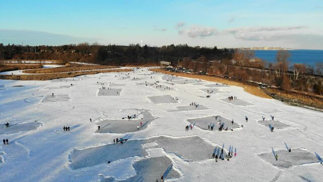 Aerial footage of people skating on a frozen pond during winter in Ontario, Canada