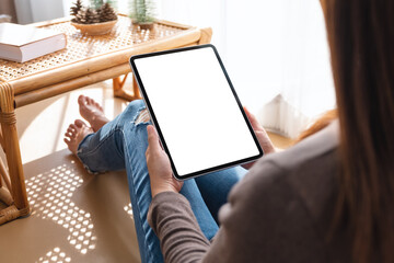 Mockup image of a woman holding and using tablet pc with blank desktop white screen at home