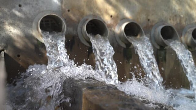 Clear Water Flows Through Row of Drain Pipes - Slow Motion