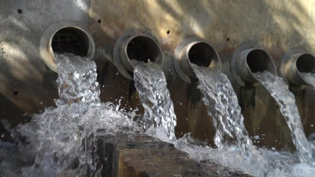 Clear Water Flows Through Row of Waste Pipes - Slowmo Footage