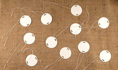 White plastic round tags for marking on burlap fabric background