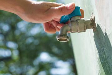 hand of woman she was using her hand to shut the flowing water from faucet.water saving and energy...