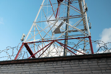 Telecommunication tower against the blue sky, with barbed wire. TV tower. Forbidden zone