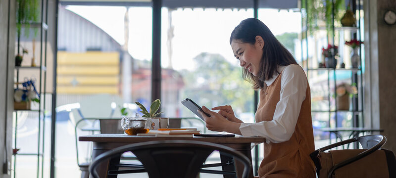 Cropped shot of freelancer businesswoman working with tablet computer at cafe terrace.