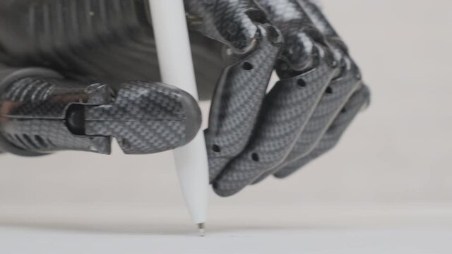 Man with bionic prosthetic hand writes pen on paper sheet close up.
