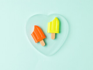 Two bitten popsicles in a glass heart on a blue background.
