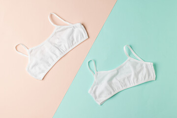 Two simple white bras on a two-tone background.