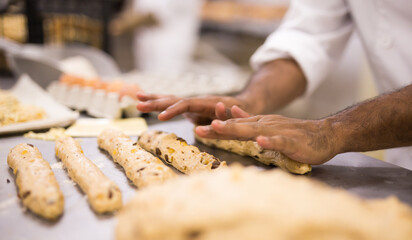 View of hands of male baker cooking bread, working with dough, forming baguettes