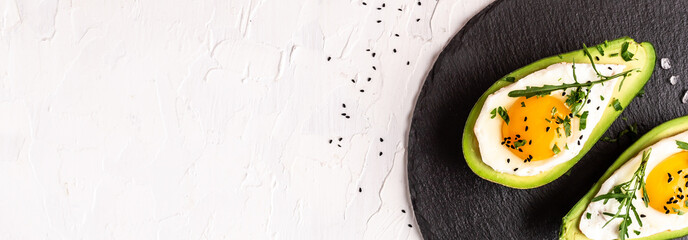 Avocado baked with eggs, fresh arugula, ground pepper on light background, Long banner format, top view