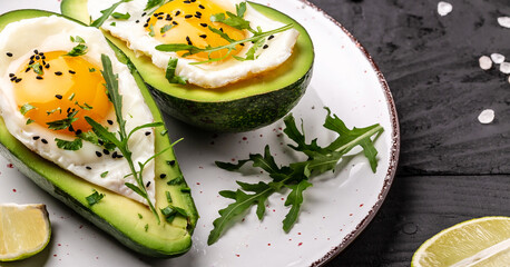 Avocado baked with eggs, fresh arugula, ground pepper on rustic background, Food recipe background. Close up, top view