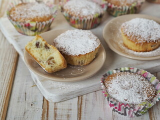 Small traditional raisin muffins in paper tins, sprinkled with powdered sugar.