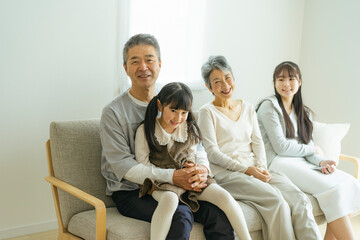 ソファに座りくつろぐシニア夫婦と孫