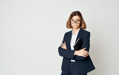 Business woman in a blue jacket and a white shirt with glasses on her face and a book in her hands