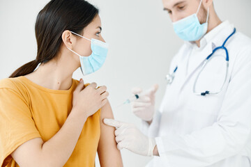 patient in a medical mask looks at the doctor with a syringe in hand covid vaccination