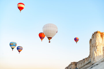 Fototapeta na wymiar Colorful air balloons flying in clear sky near huge white mountain