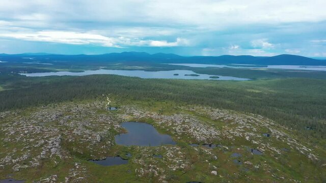 Aerial view over a bare fell, surrounded by arctic wilderness, in Lapland - reverse, pan, drone shot