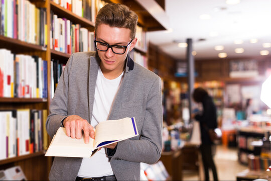 Serious positive man pointing at something in open book at bookstore