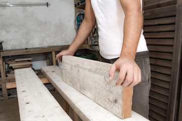 Male carpenter working with wood material in a garage.