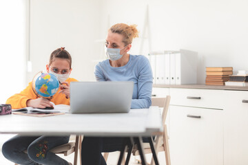 Child home studying education, homeschooling, with private tutor / mother with protective mask in the time of viruses, flu and seasonal pandemic.