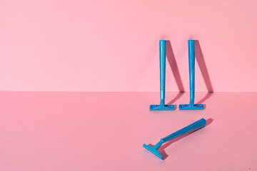 Blue disposable razors on pink paper background