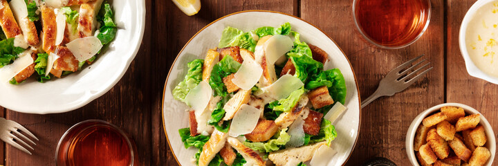 Caesar salad panoramic banner on a dark rustic wooden background, a flat lay
