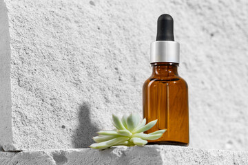 Glass jar of skincare serum on concrete block