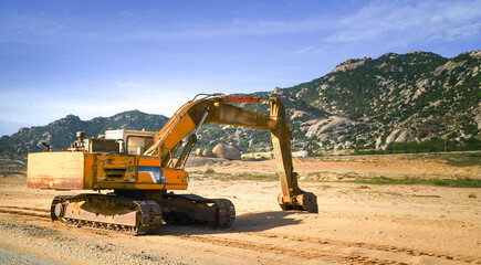 Fototapeta na wymiar Excavator on a construction site, next to a hill.