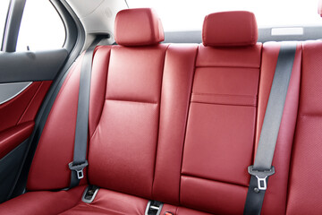 Back passenger red leather seats in modern luxury car. Red perforated leather with stitching. Car inside. Leather comfortable red seats. Car interior details