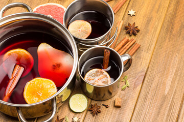 Citrus mulled wine with spices in metal mugs and saucepan