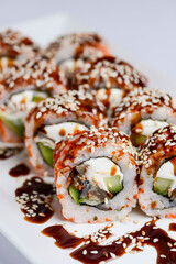 Japanese sushi set with eel and unagi sauce. Cream cheese inside. Served on a white plate.