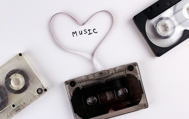 Three old audio cassettes on a white background with a film heart. Cassette heart with the words...
