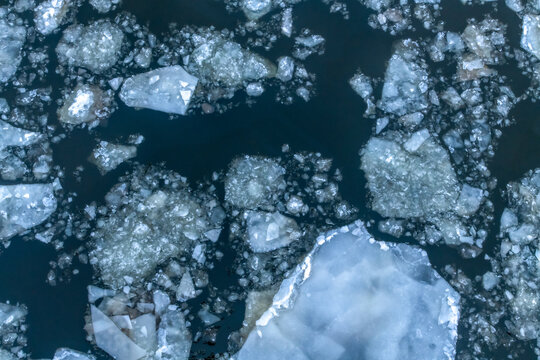Abstract winter nature background. Top view of ice drift on Moscow river, Russia. Ice floes of different sizes floats on the water. Springtime theme.