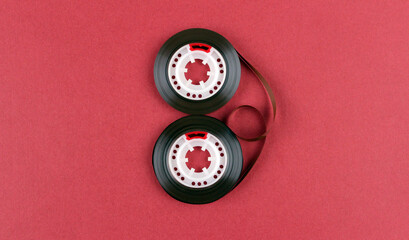 Two skeins of audio cassette tape laid out in the shape of the number 8 on a red background