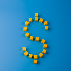 Dollar sign made with yellow wooden blocks on blue background. Top view. Currency and finance minimal concept
