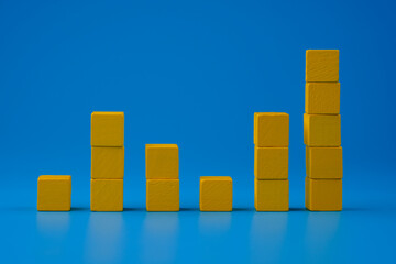 Ups and downs chart graph made with yellow wooden blocks on blue background. Trends and performance...