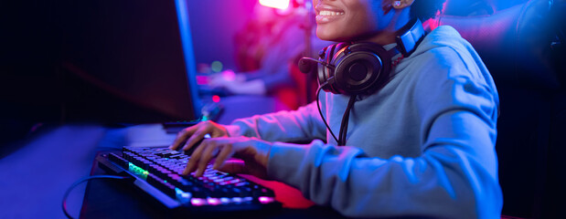 Professional cyber video gamer studio African American with personal computer armchair, keyboard for stream in neon color blur background, banner © Parilov