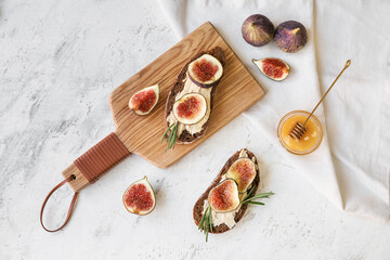 Tasty sandwiches with fig on light background
