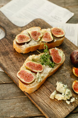 Tasty sandwiches with fig on wooden background