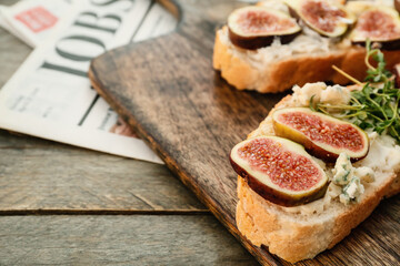 Board with tasty sandwich on wooden background
