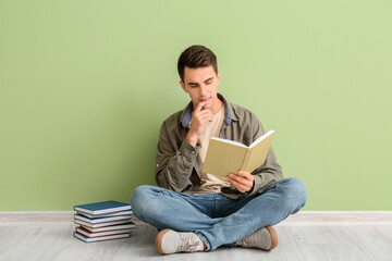 Young man reading books near color wall