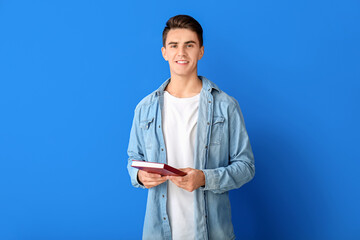 Young man with book on color background