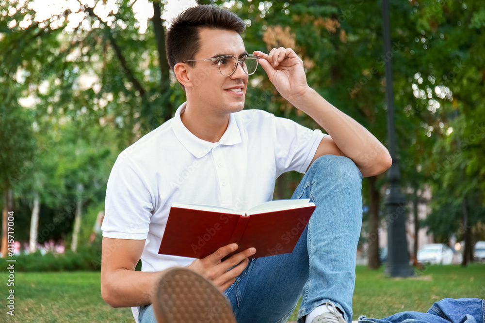 Wall mural Young man reading book in park