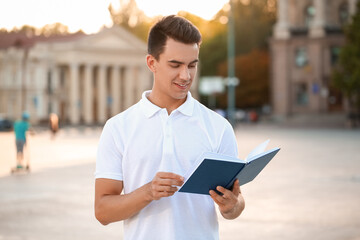 Young man reading book outdoors